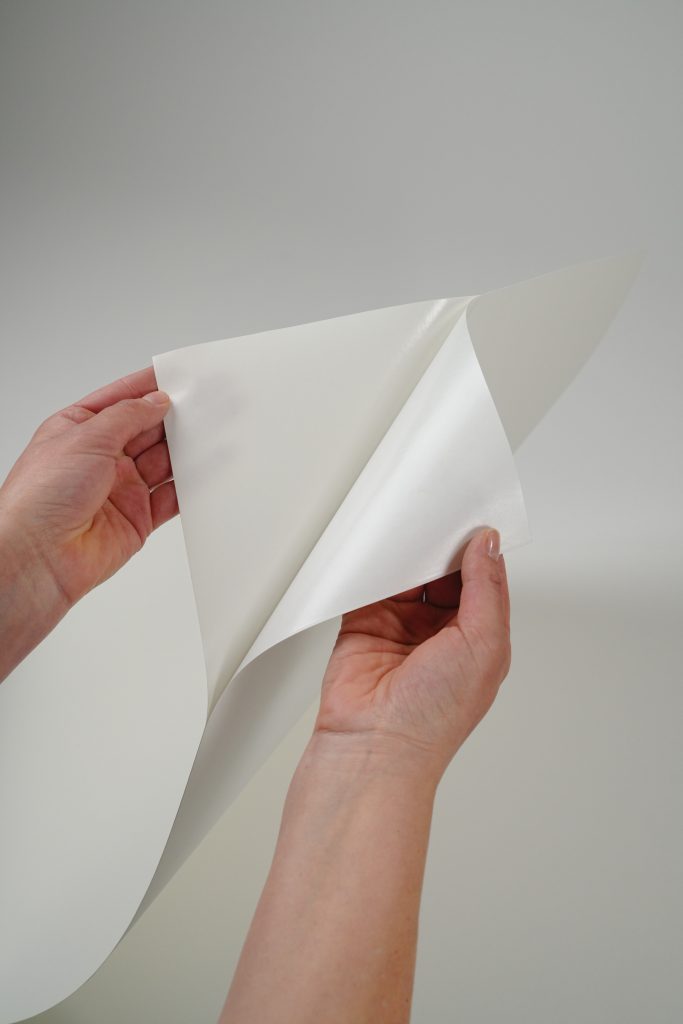 hands peeling Varitess self adhesive wallpaper from its backing sheet