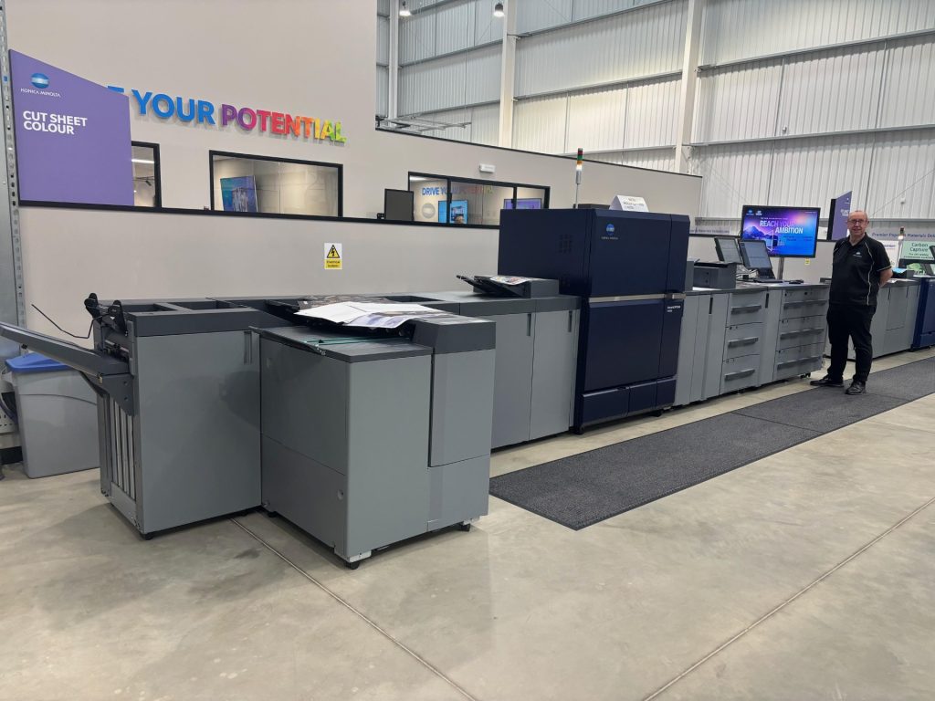 Man stands in front of huge Konica Minolta AccurioPress printer