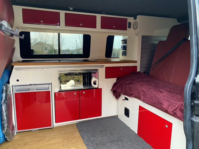 Campervan interior showing red doors with cream surounds