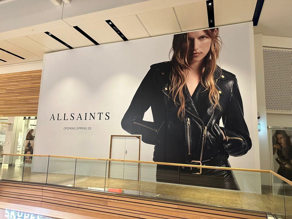 AllSaints clothing brand shopping mall advertising board showing girl in leather jacket created with drytac media by Dragon signs