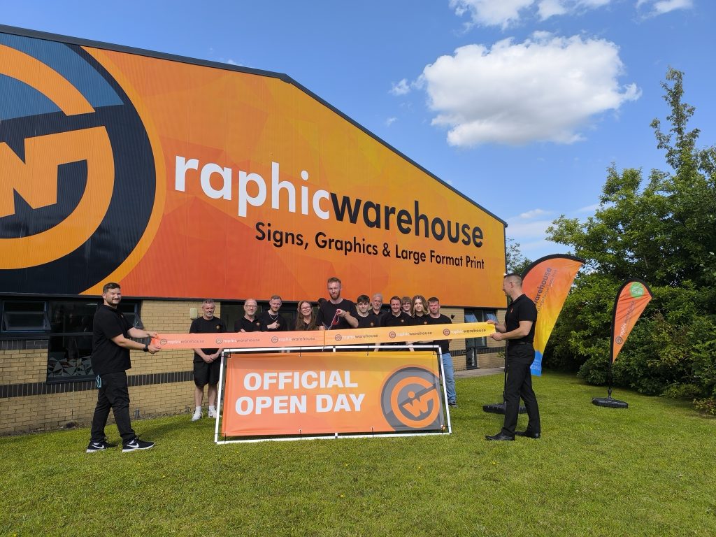 The Graphic Warehouse team celebrate the official opening of the new premises by cutting a large printed ribbon