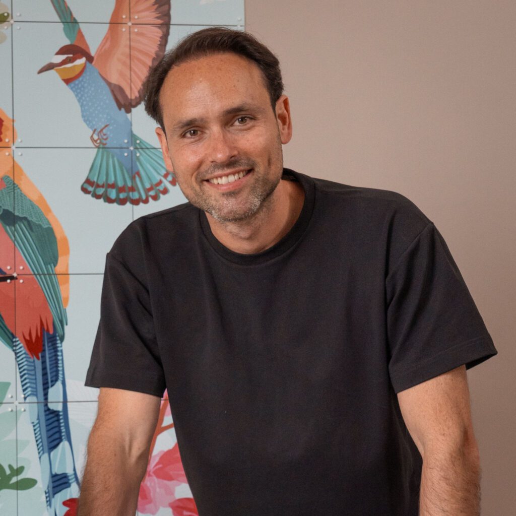 Erik-Jan Schreurs, Co-CEO and Owner of IXXI in front of colourful wall graphics made with AGFA SYNAPS