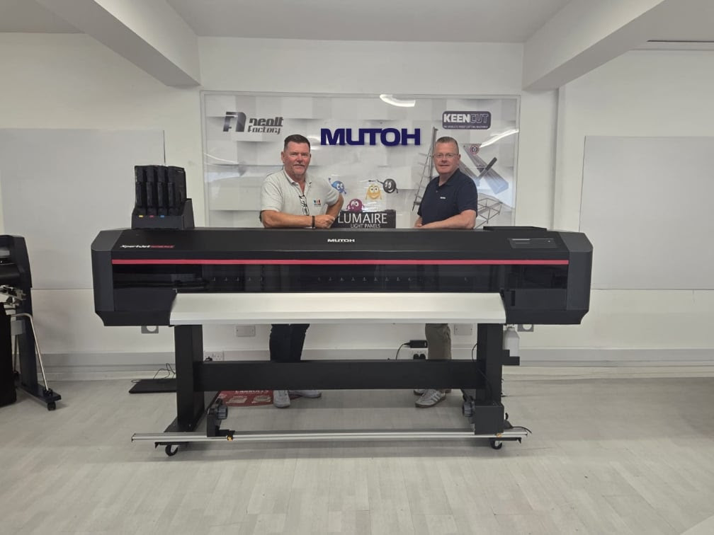 two men standing behind a large format printer.