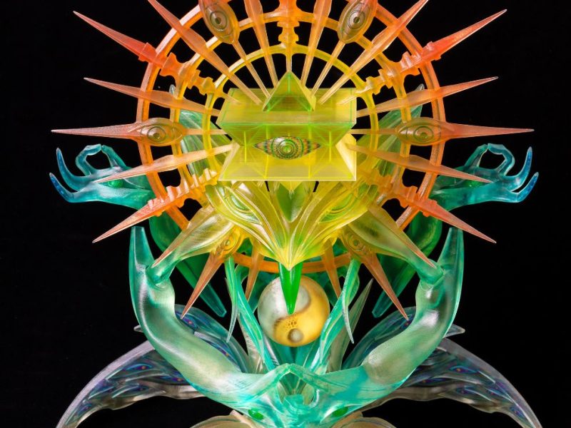A complex, vibrant 3D printed sculpture by humanoise featuring geometric shapes and spiritual motifs, utilizing clear and coloured resins