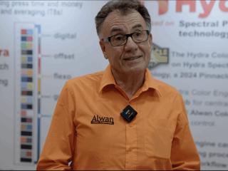 Portrait of Elie Khoury, founder of Alwan Color Expertise, standing in front of the Hydra 40 Patch Profiling Chart on the exhibit floor.