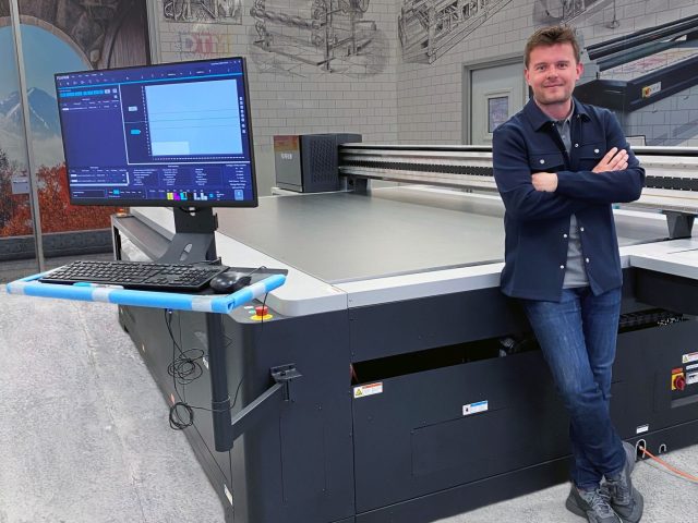 Liam Cameron, Head of Print at Peerless, stands alongside the new Fujifilm Acuity Prime L printer