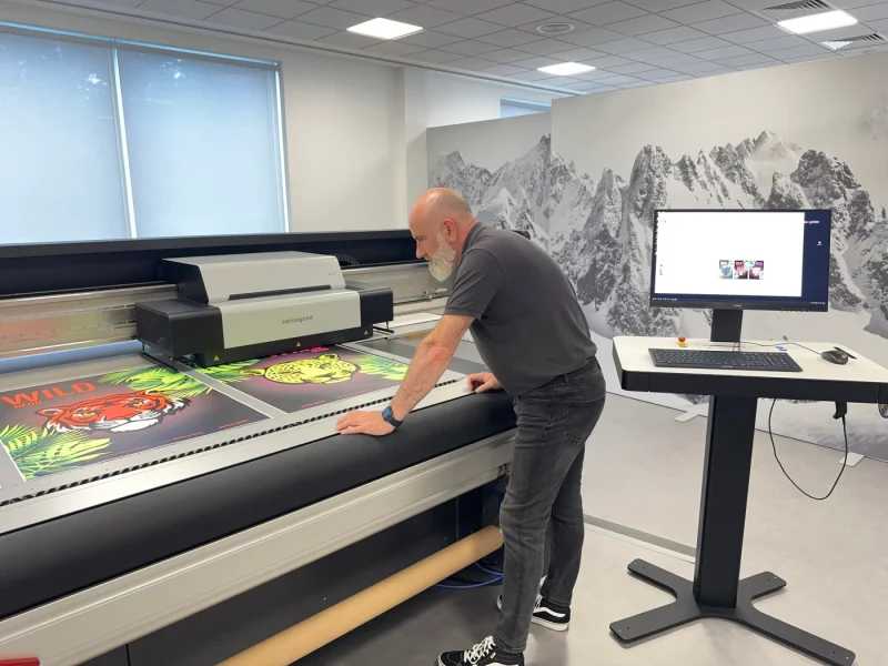 Man looks at printed images emerging from swissQprint Kudu printer