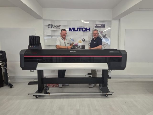 two men standing behind a large format printer.